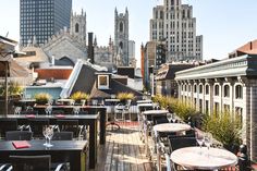 an outdoor dining area with tables and chairs in front of tall buildings on a sunny day