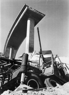 an old black and white photo of a dump truck in the sand with it's door open