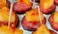 pineapple and bacon skewers with toothpicks on a white platter