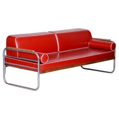 a red leather couch sitting on top of a metal frame with an armrest and foot rest