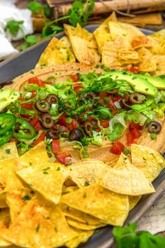 a platter filled with tortilla chips topped with lettuce and black olives