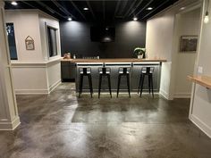 an empty room with three bar stools in the center and two bars on each side