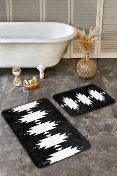 two black and white bath mats sitting on top of a bathroom floor next to a tub