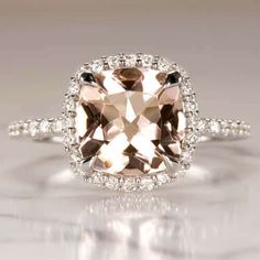 an engagement ring with a cushion cut peach morganite surrounded by white diamonds on a gray background