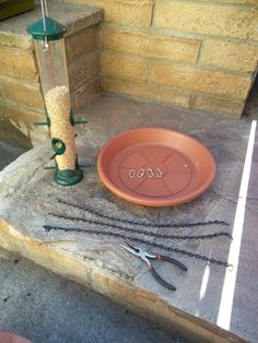 a bird feeder sitting on top of a cement slab next to scissors and a chain