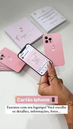 a person holding an iphone in their hand next to some pink cases on a table