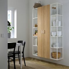 a kitchen with white walls and wooden cabinets, black chairs and a dining room table