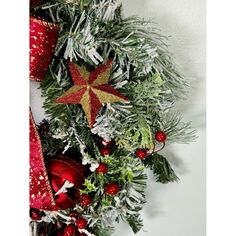 a christmas wreath with red and gold ornaments on it's side hanging from the wall