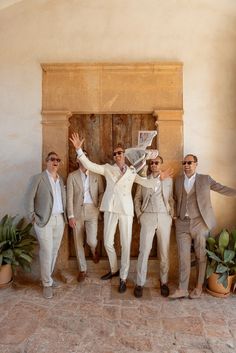 a group of men standing next to each other in front of a door wearing suits