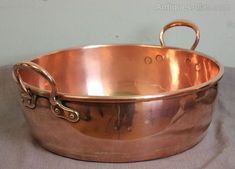 an old copper pan with handles on a table