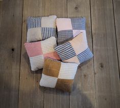 four different colored pillows sitting on top of a wooden floor next to each other,