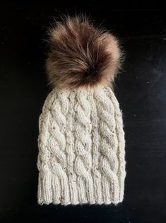 a white knitted hat with a brown pom - pom