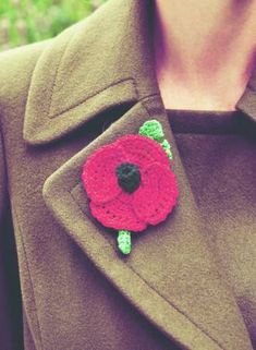 a woman wearing a coat with a crocheted flower on it