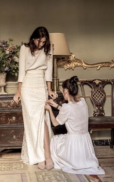 two women in white dresses are sitting on the floor