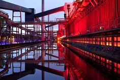 an industrial area with red lights reflecting in the water