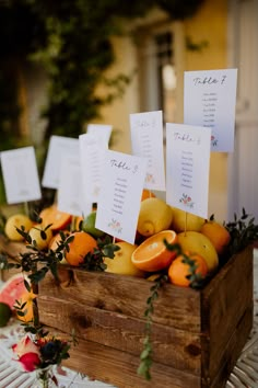 a wooden box filled with lots of fruit on top of a white tablecloth covered table