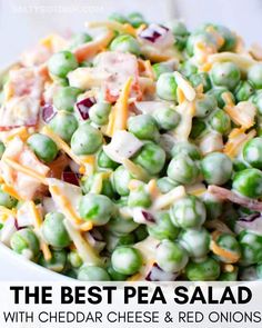 a white bowl filled with peas and cheese on top of a wooden table next to a fork