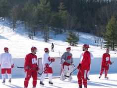 a group of young men standing next to each other on top of snow covered ground