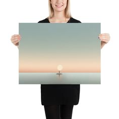 a woman holding up a poster with the sun setting