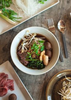 a white bowl filled with meat and veggies on top of a wooden table