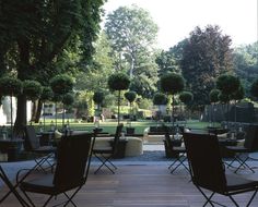 there are many chairs and tables outside on the deck in the yard, but no one is around them