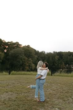 a man and woman hug each other in the middle of a field