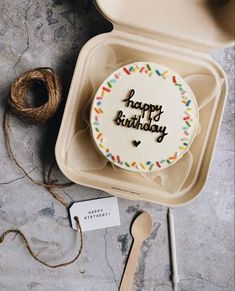 a happy birthday cake with sprinkles in a box next to some twine