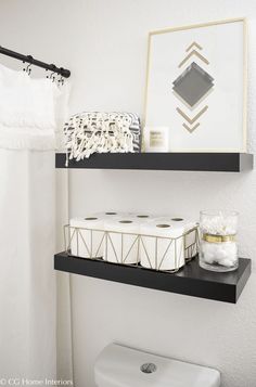 two black shelves above a toilet in a bathroom