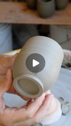 a person is holding a clay vase in their hand and touching it with the thumb