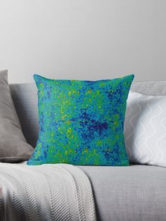 a blue and green throw pillow sitting on top of a couch next to two pillows