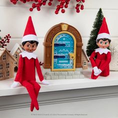 two elfs sitting on top of a mantle with christmas decorations