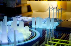 a model of wind turbines and buildings in a room with other models on the table