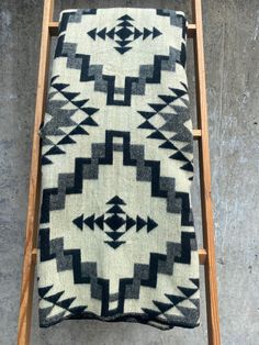 a black and white blanket sitting on top of a wooden ladder