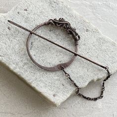 a piece of metal sitting on top of a white stone wall next to a chain