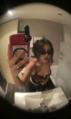 a woman taking a selfie with her cell phone in front of the camera mirror