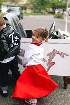 two young children standing next to each other in front of a white and red sign