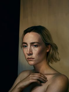 a woman with freckled hair and blue eyes is posing for a photo in front of a wall