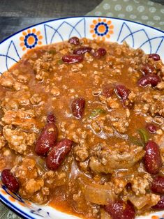 a bowl filled with meat and beans on top of a table