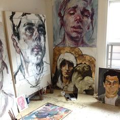 an artist's studio with several paintings on the wall