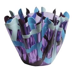 a purple glass vase filled with lots of blue and black objects on top of a white surface