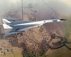 an aerial view of a fighter jet flying in the sky over a town and fields