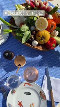 an arrangement of fruits and vegetables on a blue table cloth, with utensils