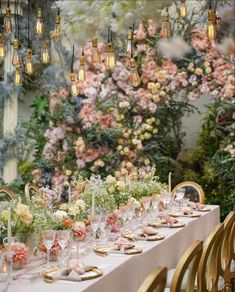 a long table is set with flowers and goldware for an elegant wedding reception in the garden