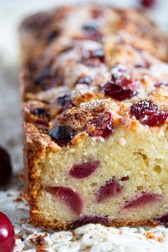 a close up of a cake with cranberry toppings and powdered sugar