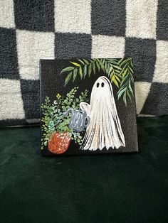 a black and white checkered blanket with a painting of a ghost holding a potted plant