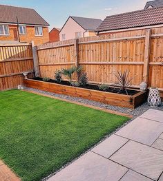 a backyard with grass and wooden fenced in area next to the yard is an artificial lawn