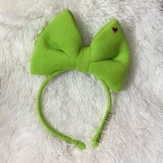 a green bow headband on top of a white fur covered bed with a hair comb