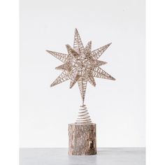 a christmas tree topper with a star on it sitting on a wooden stump in front of a white background