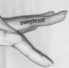 two fingers with the words sweetener tattooed on them are shown in black and white