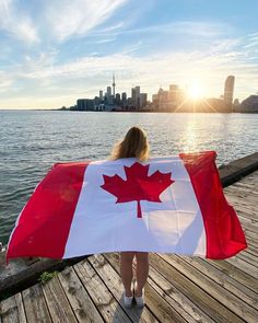 a woman holding a canadian flag on a dock